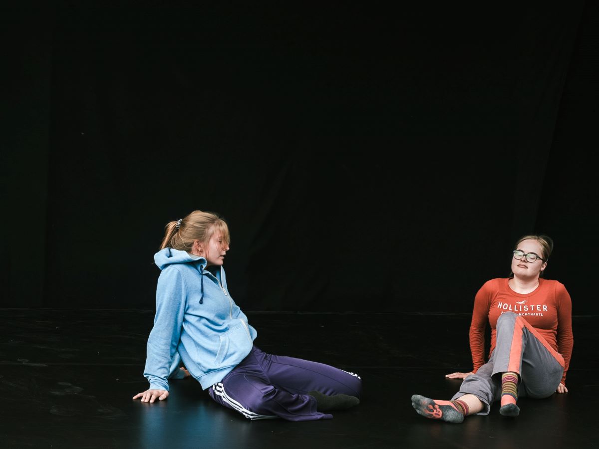 Zwei Jugendliche sitzen auf einem Tanzboden.