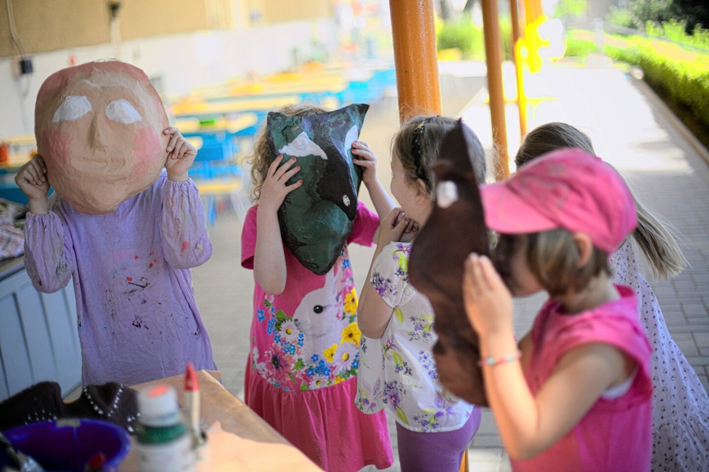 Mehrere Kinder halten sich selbstgebastelte Masken vor die Gesichter.