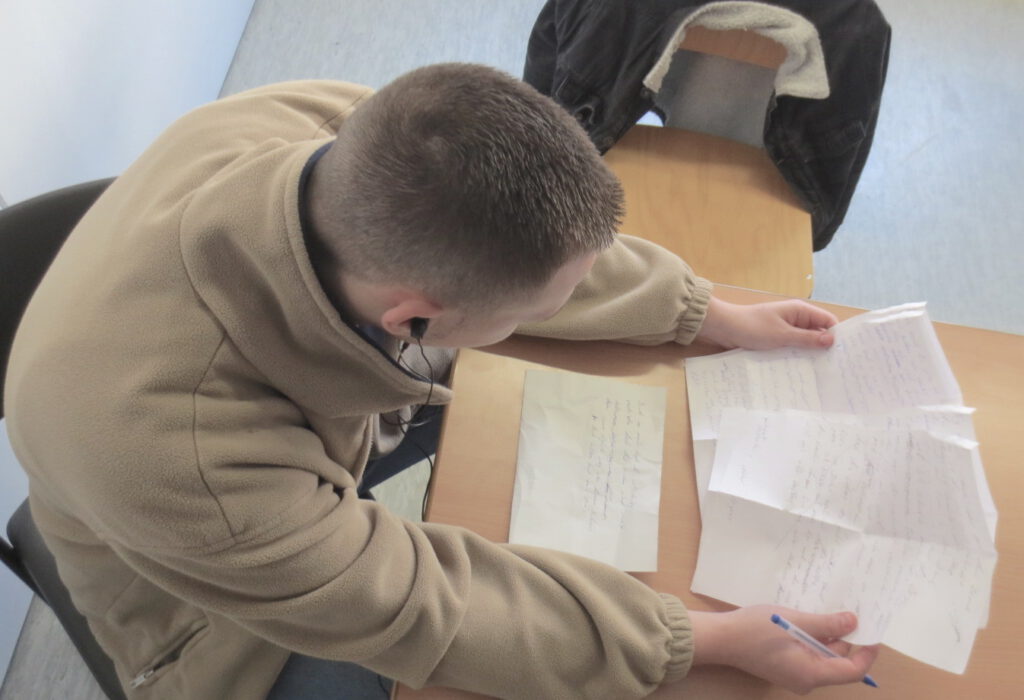 Ein Jugendlicher sitzt an einem Tisch und arbeitet an einem Text.